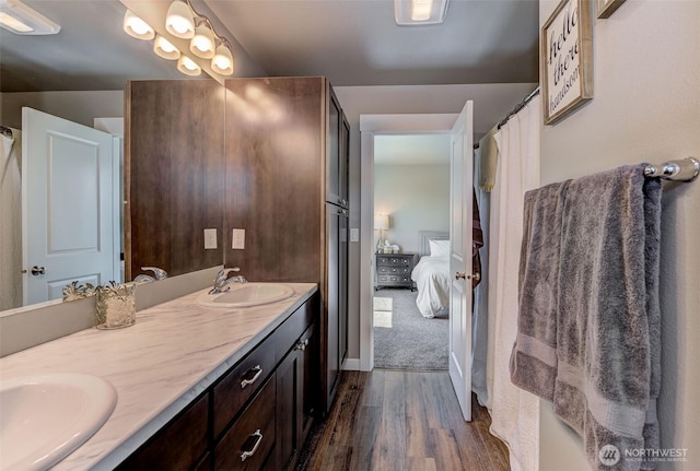 ensuite bathroom featuring a sink, ensuite bathroom, double vanity, and wood finished floors