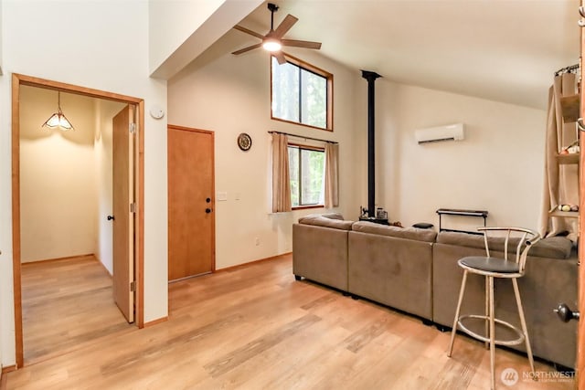 17936 Clearland Blvd SE, Yelm, WA 98597 - living area with ceiling fan, a wood stove, a wall unit AC, light wood-style flooring, and high vaulted ceiling