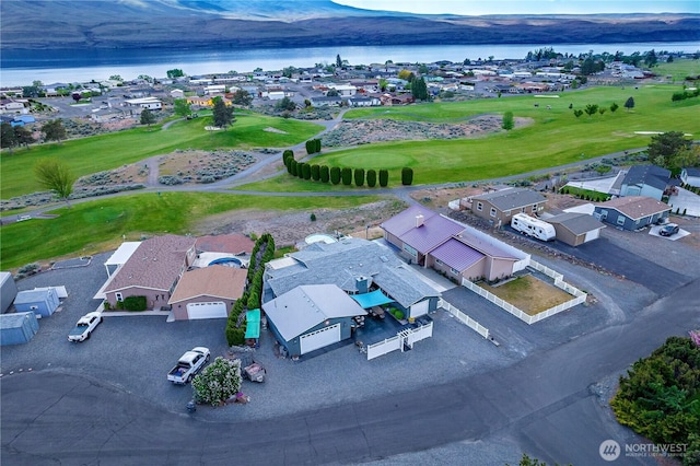 drone / aerial view with a water and mountain view, golf course view, and a residential view