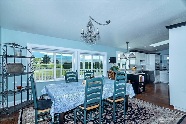 dining area featuring an inviting chandelier, plenty of natural light, and dark wood finished floors