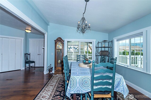 dining area featuring vaulted ceiling, wood finished floors, a chandelier, and a wealth of natural light
