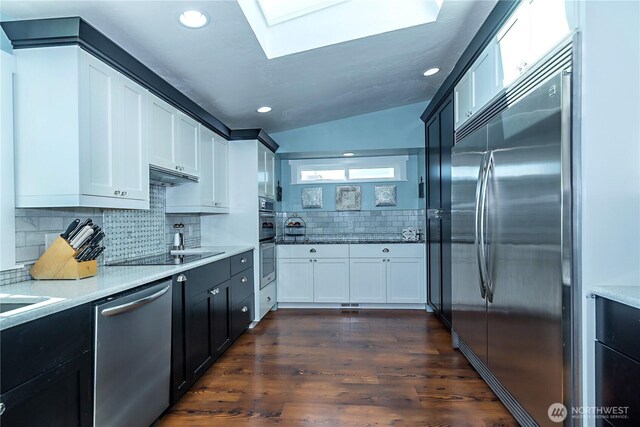 kitchen with stainless steel appliances, recessed lighting, decorative backsplash, dark wood-type flooring, and a skylight