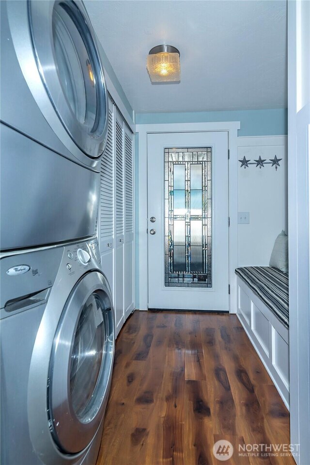 laundry room with stacked washer / drying machine, wood finished floors, and laundry area