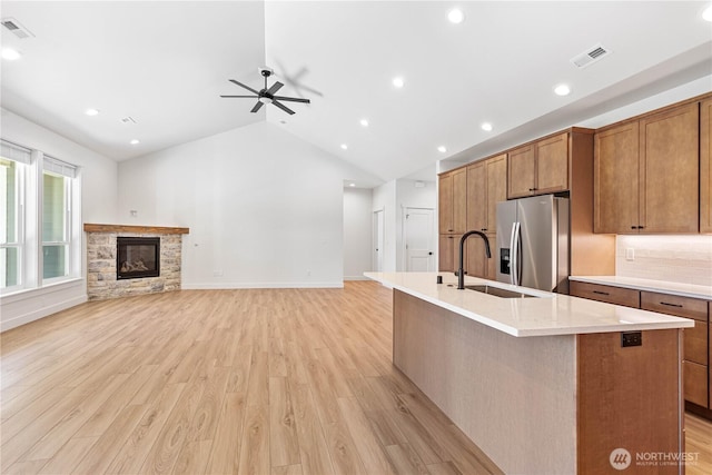 1200 E Georgia Ln, Everson, WA 98247 - kitchen featuring stainless steel fridge, light wood-type flooring, a kitchen island with sink, a fireplace, and ceiling fan