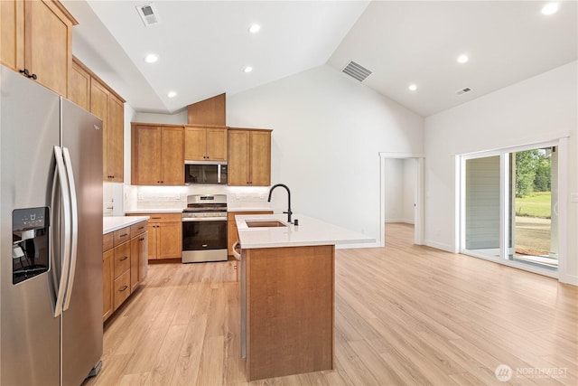 1200 E Georgia Ln, Everson, WA 98247 - kitchen with stainless steel appliances, light countertops, high vaulted ceiling, light wood finished floors, and a center island with sink