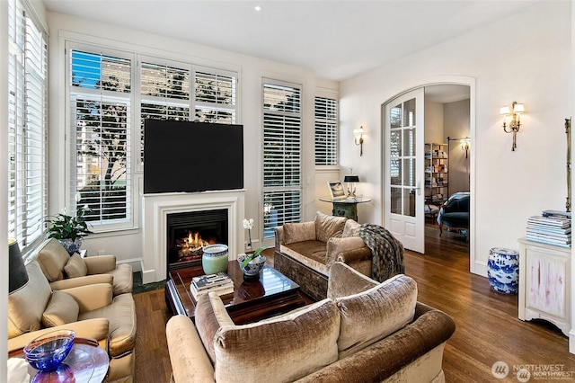 2801 1st Ave Unit 113, Seattle, WA 98121 - living room featuring arched walkways, wood finished floors, healthy amount of natural light, and a warm lit fireplace
