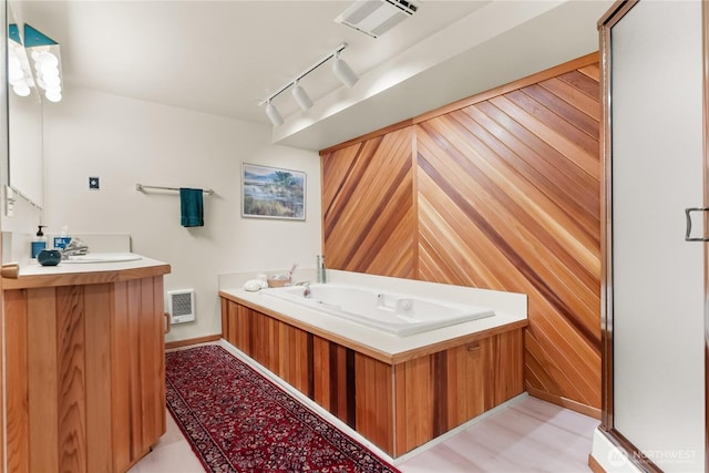full bathroom featuring vanity, rail lighting, wood walls, baseboards, and visible vents