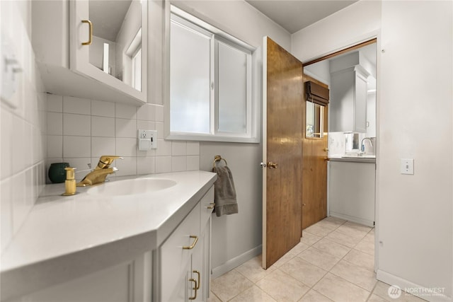 bathroom with vanity, decorative backsplash, baseboards, and tile patterned flooring