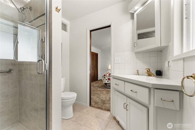 bathroom with tile patterned flooring, decorative backsplash, vanity, toilet, and a stall shower