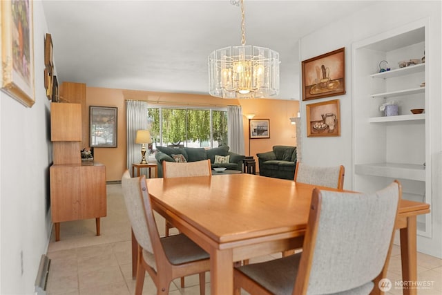 dining space with light tile patterned flooring, a chandelier, and built in features