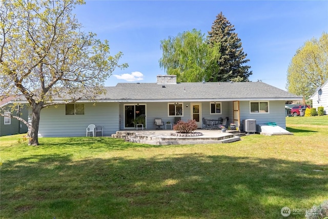 rear view of property featuring a patio, a chimney, a yard, and central AC unit