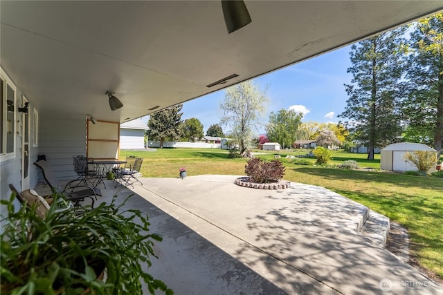 view of patio featuring outdoor dining space, an outbuilding, and a shed