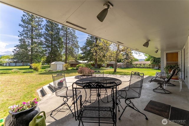 view of patio / terrace with a storage shed, fence, an outbuilding, and outdoor dining area
