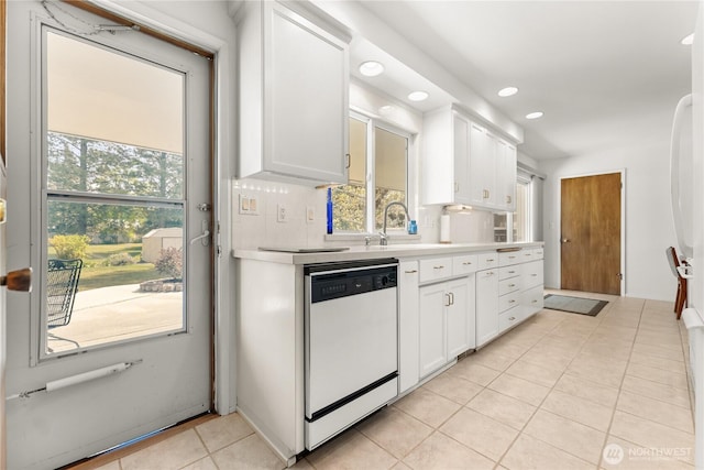 kitchen featuring white dishwasher, light tile patterned floors, white cabinetry, and a healthy amount of sunlight