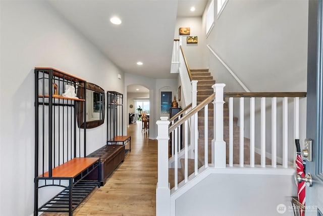 stairs with recessed lighting, arched walkways, and wood finished floors