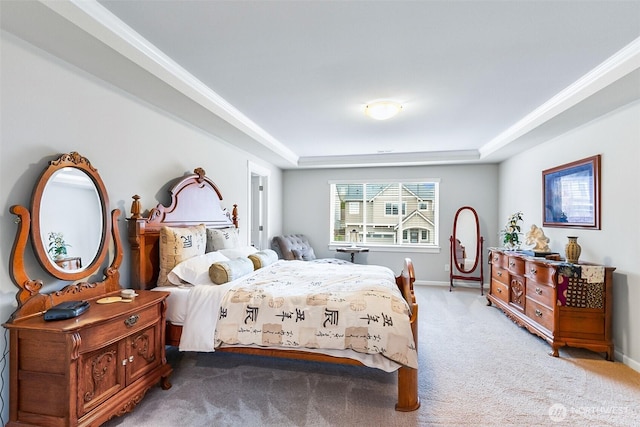 bedroom with light colored carpet, a tray ceiling, and baseboards