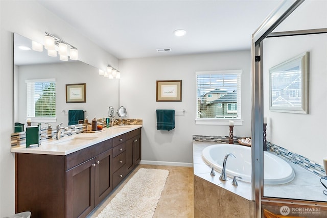 bathroom with a sink, double vanity, visible vents, tile patterned floors, and a garden tub