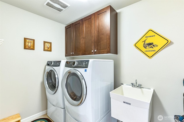 laundry room with visible vents, washing machine and dryer, cabinet space, and a sink