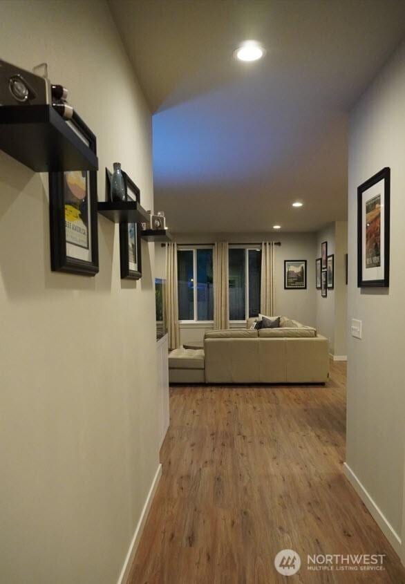 corridor featuring baseboards, recessed lighting, and wood finished floors