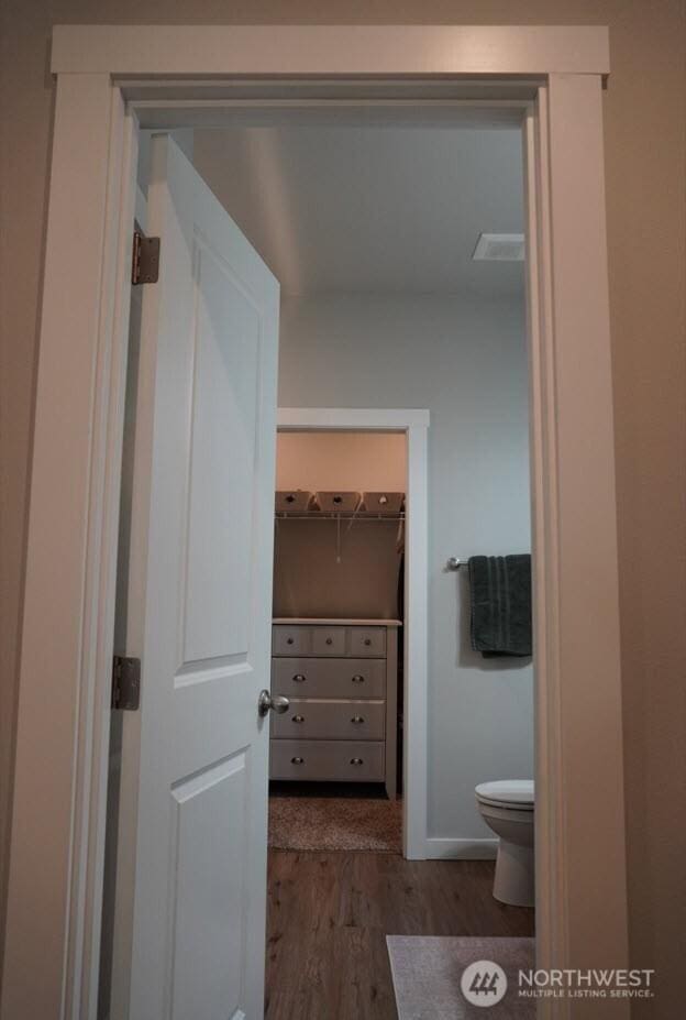 bathroom featuring visible vents, wood finished floors, a spacious closet, and toilet