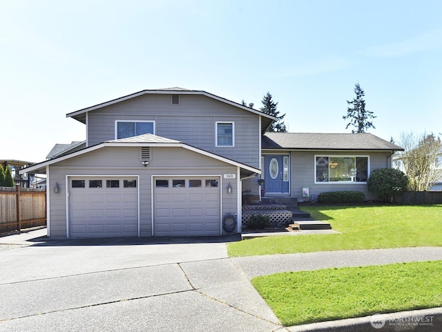 tri-level home featuring fence, driveway, a front lawn, and a garage
