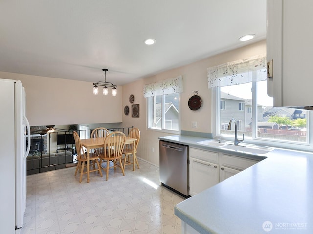 kitchen featuring stainless steel dishwasher, freestanding refrigerator, light floors, white cabinetry, and a sink