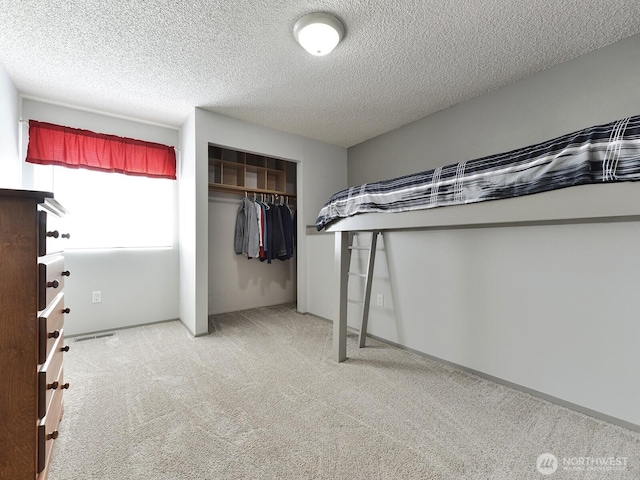 unfurnished bedroom featuring a textured ceiling, visible vents, carpet, and a closet