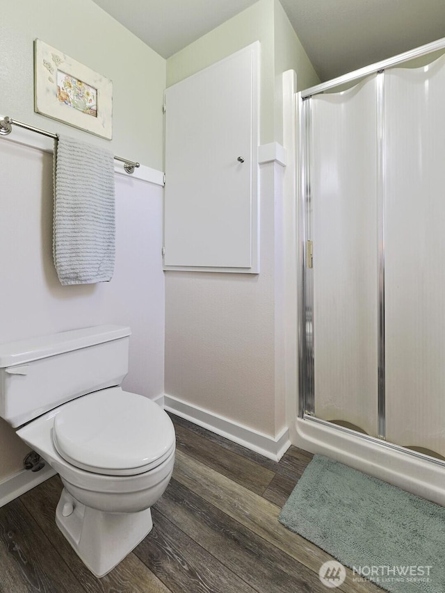 full bath with baseboards, a stall shower, and wood finished floors