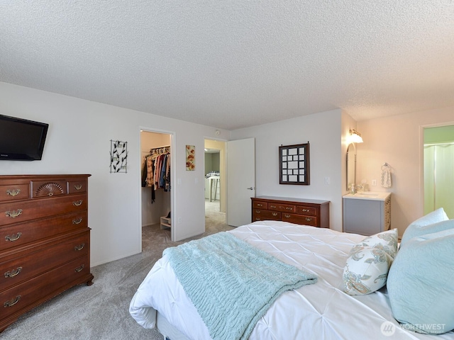 bedroom featuring a spacious closet, a closet, a textured ceiling, and light colored carpet