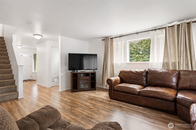 living area featuring baseboards, stairs, and wood finished floors