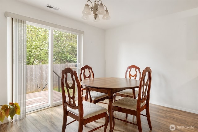 dining space with an inviting chandelier, baseboards, wood finished floors, and visible vents