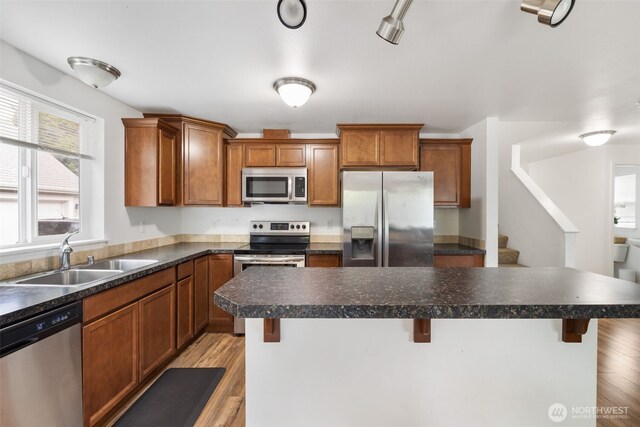 kitchen featuring a sink, dark countertops, stainless steel appliances, and a kitchen bar