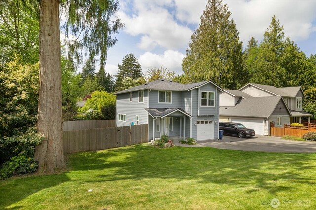 view of front of property featuring fence, concrete driveway, and a front lawn