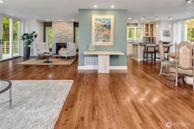 living room featuring recessed lighting, wood finished floors, visible vents, and a fireplace