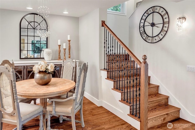dining space with wood finished floors, stairway, baseboards, an inviting chandelier, and recessed lighting