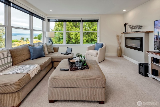 living area featuring carpet flooring, baseboards, and a glass covered fireplace