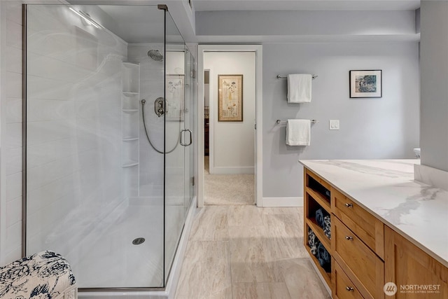 full bathroom featuring vanity, baseboards, and a shower stall