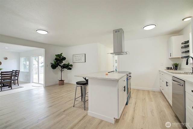12120 218th Avenue Ct E, Bonney Lake, WA 98391 - kitchen with a breakfast bar, light wood-style floors, island range hood, a sink, and stainless steel appliances