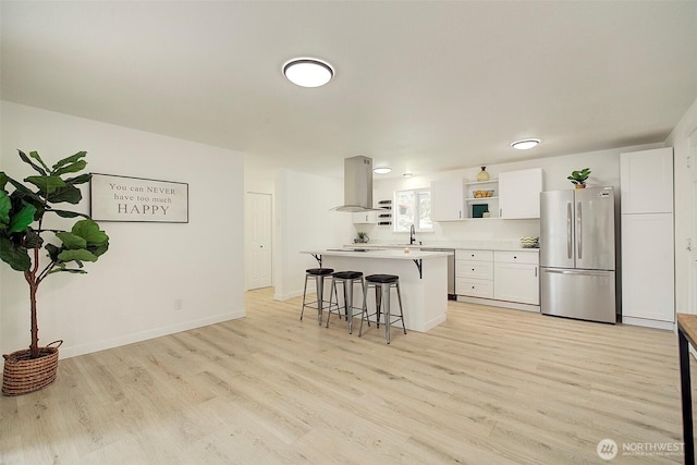12120 218th Avenue Ct E, Bonney Lake, WA 98391 - kitchen with freestanding refrigerator, a breakfast bar, white cabinets, island exhaust hood, and light wood finished floors