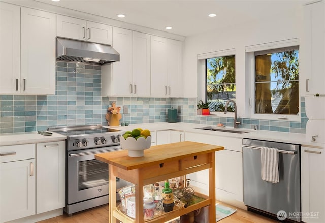 10419 41st Ave SW Unit A & B, Seattle, WA 98146 - kitchen with stainless steel appliances, under cabinet range hood, light countertops, white cabinetry, and backsplash