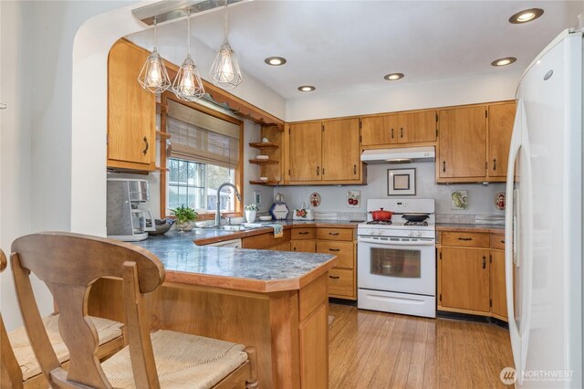 kitchen featuring a peninsula, white appliances, light wood-type flooring, under cabinet range hood, and a sink
