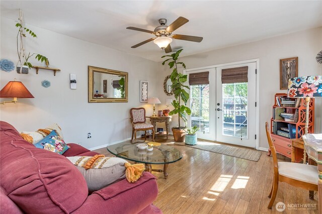 living area featuring wood-type flooring, a ceiling fan, baseboards, and french doors