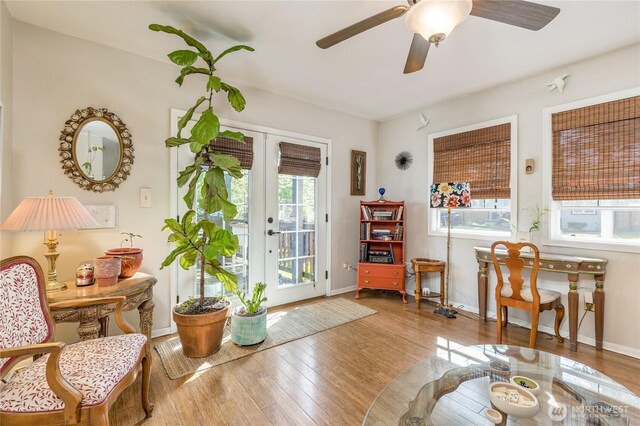 living area featuring french doors, a ceiling fan, baseboards, and hardwood / wood-style floors
