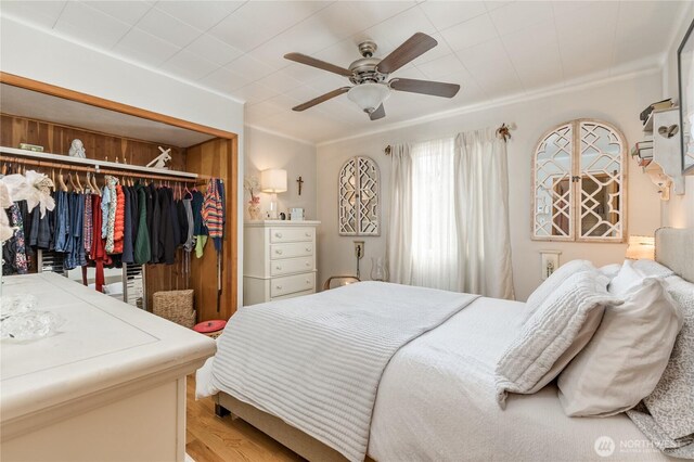 bedroom featuring crown molding, ceiling fan, light wood finished floors, and a closet