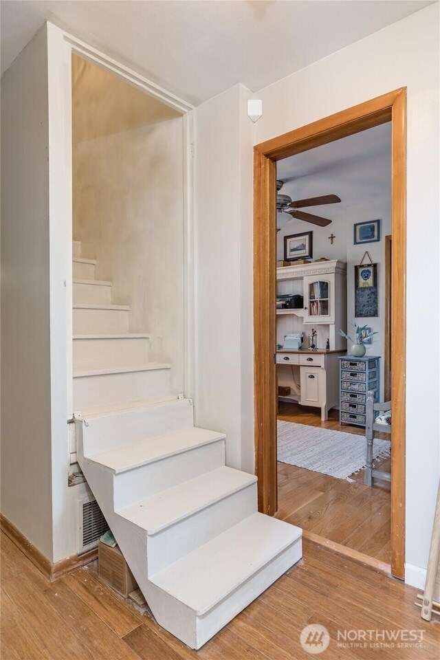 stairs with a ceiling fan, baseboards, and wood finished floors