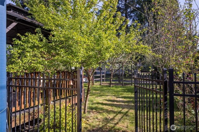 view of gate featuring a lawn and a fenced backyard