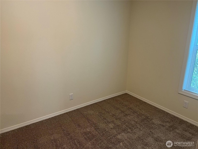 spare room with dark colored carpet and baseboards