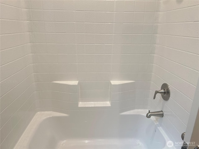 interior details featuring washtub / shower combination