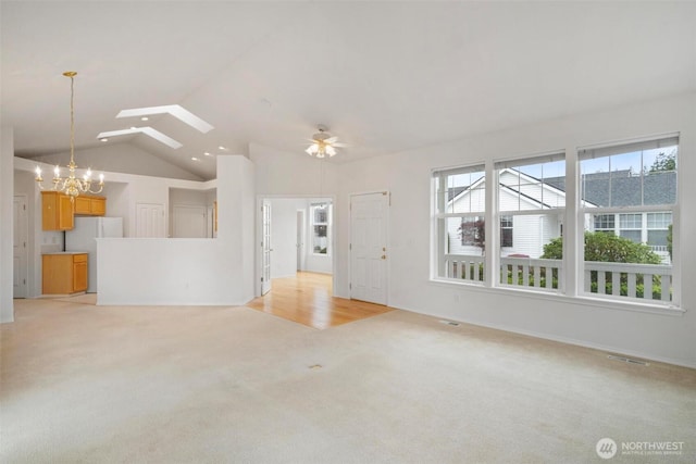823 Landing Way, Centralia, WA 98531 - unfurnished living room featuring ceiling fan with notable chandelier, light colored carpet, visible vents, and vaulted ceiling with skylight