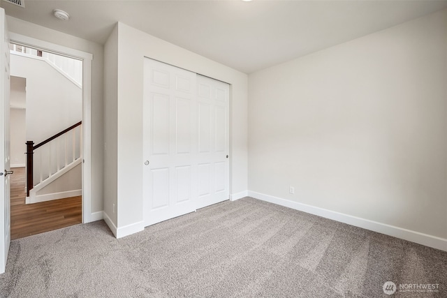 unfurnished bedroom with a closet, baseboards, carpet flooring, and visible vents